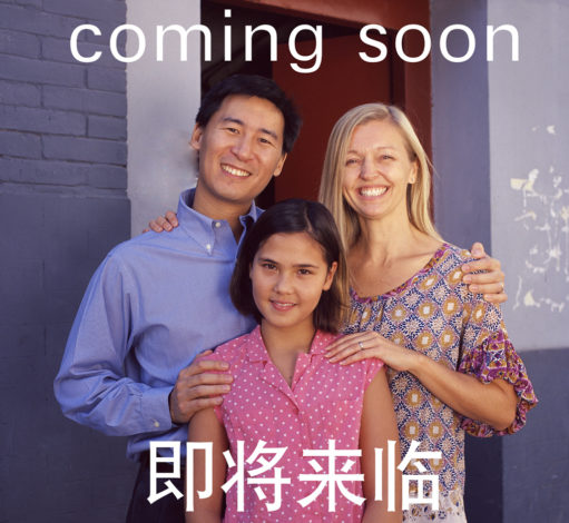 vor dem NS-Dokumentationszentrum steht ein Billboard, auf dem eine multikulturelle Kleinfamilie zu sehen ist Darauf steht oben "Coming soon", darunter vier asiatische Schriftzeichen