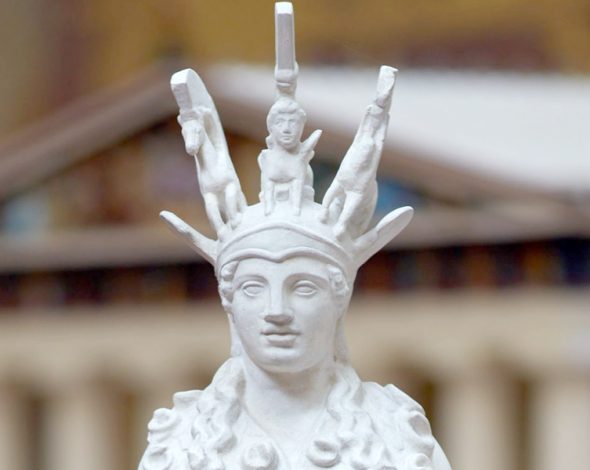 Das Bild zeigt eine Frau bis zu ihrer Brust. Es ist eine weiße Statue aus Gips. Die Frau hat einen Helm auf ihrem Kopf.